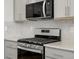 Modern gas range with stainless steel backsplash, microwave and gray cabinets at 742 N Tempe St, Aurora, CO 80018