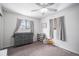 Bright bedroom features neutral carpet, ceiling fan, gray changing table, and two windows with light-filtering gray curtains at 7746 W Quarto Dr, Littleton, CO 80128