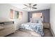 Comfortable bedroom with a floral-patterned bedspread, neutral walls, and a ceiling fan at 7746 W Quarto Dr, Littleton, CO 80128