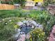 Lush backyard features a rock-rimmed pond, lighting, and a manicured lawn, perfect for relaxation and entertaining at 3216 S Granby Way, Aurora, CO 80014