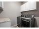 Well-lit laundry room featuring a modern washer and dryer set, along with white cabinets for ample storage at 2080 Shadow Creek Dr, Castle Rock, CO 80104