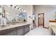 Elegant bathroom featuring a granite countertop, decorative mirror, and access to a second bathroom at 11666 W 74Th Way, Arvada, CO 80005