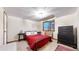 Comfortable bedroom with a red bed, dark furniture, and natural light at 11666 W 74Th Way, Arvada, CO 80005