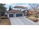 Two-story home with three-car garage, featuring manicured lawn and charming front yard with mature trees at 11666 W 74Th Way, Arvada, CO 80005