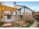 Backyard with paver patio, wooden pergola, dining set, shrubs, ivy, stone border, and white siding at 9094 W 103Rd Ave, Broomfield, CO 80021