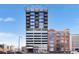 Modern high-rise building with parking garage and mixed brick-and-glass exterior under a clear blue sky at 2020 Arapahoe St # 1150, Denver, CO 80205