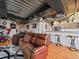 Loft living room featuring a leather sofa, industrial ceilings, hardwood floors, and an open kitchen at 2020 Arapahoe St # 1150, Denver, CO 80205