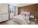 Inviting bedroom features a wood accent wall and a light-filled window, creating a warm and relaxing retreat at 8896 W Teton Cir, Littleton, CO 80128
