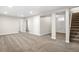 Open basement layout with carpeting, white support pillars, and access to stairs at 14441 Maxwell Pl, Denver, CO 80239