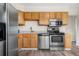 The kitchen has stainless steel appliances, wooden cabinets, granite countertops, and wood-look flooring at 14441 Maxwell Pl, Denver, CO 80239