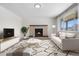 Bright living room with brick fireplace, wood floors, modern rug, and neutral-toned furniture at 14441 Maxwell Pl, Denver, CO 80239