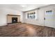 Cozy living room with a brick fireplace, wood floors, a large window, and a white front door at 14441 Maxwell Pl, Denver, CO 80239