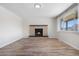 Living room with brick fireplace, wood floors, and a large window for natural light at 14441 Maxwell Pl, Denver, CO 80239