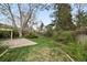 Spacious backyard featuring lush green grass, mature trees, and a concrete patio at 9004 E Floyd Ave, Denver, CO 80231