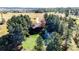 Aerial view of home surrounded by lush trees with firepit, green lawns and circular driveway at 2231 Meadow Green Cir, Franktown, CO 80116