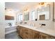 Bright bathroom featuring double sinks, wood cabinets, and soaking tub at 2231 Meadow Green Cir, Franktown, CO 80116