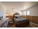Serene bedroom boasts wood paneling, plush bedding, and picturesque window view at 2231 Meadow Green Cir, Franktown, CO 80116
