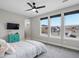 This bedroom features a modern ceiling fan, neutral walls and carpet, and large bright windows overlooking a neighborhood at 730 Edenborn Pl, Castle Rock, CO 80104
