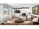 Bright living room features a stone fireplace, large windows, and stylish leather sofas with bright hardwood flooring at 13000 Willow Ln, Golden, CO 80401