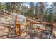 Deck with table and chairs next to a greenhouse in a wooded lot at 27407 Upper Cold Spg Gulch Rd, Golden, CO 80401