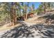 Exterior shot of a charming home nestled amongst towering trees with a long, winding driveway at 27407 Upper Cold Spg Gulch Rd, Golden, CO 80401