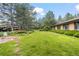 Lush backyard with manicured lawn, mature trees, and vibrant flower beds create a serene outdoor space at 7351 Poppy Way, Arvada, CO 80007
