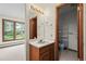 Bathroom featuring a single vanity, mirror and a view of the backyard through the window at 7351 Poppy Way, Arvada, CO 80007