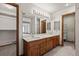 Bathroom featuring double sinks, large mirrors, wood cabinets, and plenty of lighting at 7351 Poppy Way, Arvada, CO 80007