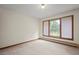 Bedroom featuring neutral carpet and trim with views of the yard through large windows at 7351 Poppy Way, Arvada, CO 80007