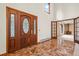 Elegant entry foyer featuring a dark wood door and red marble tile flooring at 7351 Poppy Way, Arvada, CO 80007