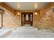 An elegant wood front door with stained glass and sidelights surrounded by brick and sconces at 7351 Poppy Way, Arvada, CO 80007