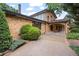 Brick home featuring a covered driveway, arched entryway, and mature landscaping at 7351 Poppy Way, Arvada, CO 80007