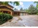 A three car garage exterior with mature trees overhead and large driveway at 7351 Poppy Way, Arvada, CO 80007