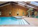 Bright indoor pool with skylights, wood walls, vaulted ceiling, and adjacent hot tub at 7351 Poppy Way, Arvada, CO 80007