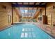 Bright indoor pool with brick BBQ, skylights, wood walls, vaulted ceiling, and adjacent hot tub at 7351 Poppy Way, Arvada, CO 80007
