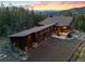 Aerial view of mountain home featuring garages, large roof, and stone accents at 5976 Stone Creek Dr, Evergreen, CO 80439