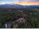 Aerial view of secluded mountain home surrounded by dense forest at sunset at 5976 Stone Creek Dr, Evergreen, CO 80439