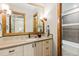 Beautiful bathroom features a wood vanity with a decorative mirror, sconces, and tiled shower at 5976 Stone Creek Dr, Evergreen, CO 80439