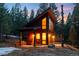 Twilight image of modern two story home with wooden siding surrounded by forest at 5976 Stone Creek Dr, Evergreen, CO 80439