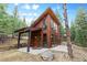 Charming wood cabin featuring a covered porch, large windows, and surrounded by a lush forest at 5976 Stone Creek Dr, Evergreen, CO 80439