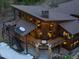 Aerial view of home with tiered balconies, outdoor seating, stone accents, and a chimney at 5976 Stone Creek Dr, Evergreen, CO 80439