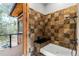 Updated shower with brown and tan tiled walls and a black bench and showerhead at 5976 Stone Creek Dr, Evergreen, CO 80439