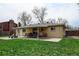Brick home backyard featuring a covered patio, outdoor dining area, and spacious green grass at 6020 Quail St, Arvada, CO 80004