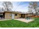 Backyard featuring a covered patio, mature trees, and a well-maintained lawn at 6020 Quail St, Arvada, CO 80004