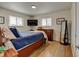 Bedroom features wood floors, two windows, and a full size bed at 6020 Quail St, Arvada, CO 80004