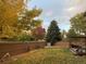 A serene fenced backyard featuring vibrant autumn foliage and a cozy deck area for relaxation at 16119 E Prentice Ln, Centennial, CO 80015