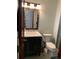 A half-bathroom with a black vanity, toilet, decorative mirror, and a doorway at 16119 E Prentice Ln, Centennial, CO 80015