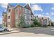 Apartment building exterior boasts brick and gray siding, complemented by lush landscaping and a well-maintained facade at 14221 E 1St Dr # 208, Aurora, CO 80011