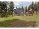 Spacious backyard with a fenced-in garden area and a red outbuilding at 8626 Junco Trl, Evergreen, CO 80439