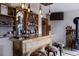 Close-up of a wooden bar with barstools, liquor shelves, and custom lighting fixtures at 8626 Junco Trl, Evergreen, CO 80439